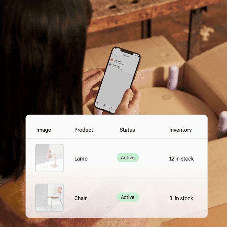 Person checking a Shopify customer dashboard on a phone next to a product inventory table
